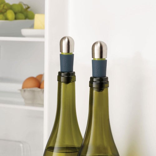 Two green wine bottles with metal bottle stoppers on a white background