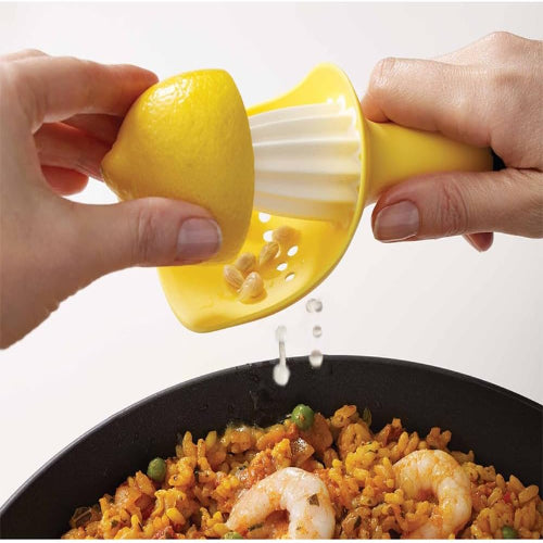 Person squeezing a lemon over a dish of paella on a white background