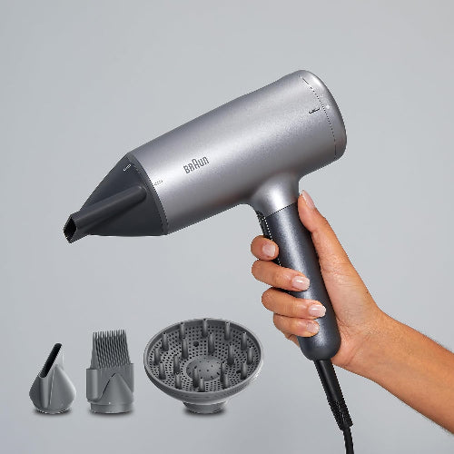 Silver Braun hair dryer with attachments on a gray background