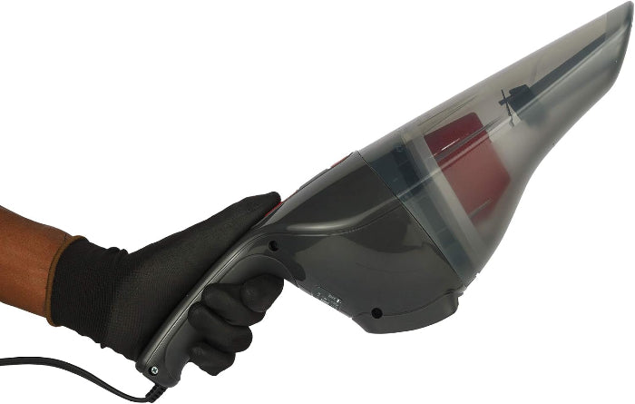 A handheld cordless vacuum cleaner with a transparent dust bin and a red filter compartment, held by a hand wearing a black glove against a plain white background.