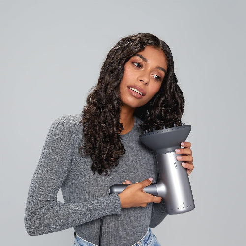 Woman holding a hair dryer against a gray background