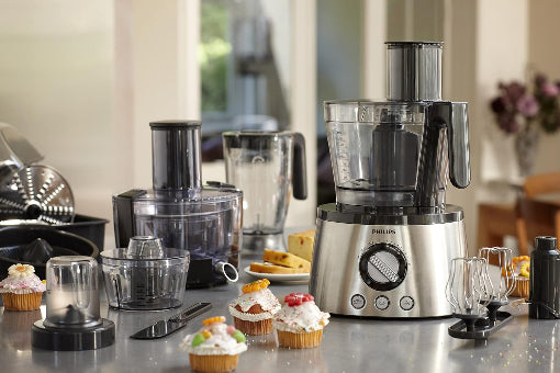 Kitchen appliances including a food processor and blender on a countertop with cupcakes.