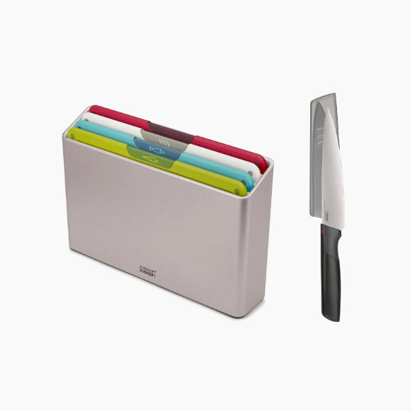 A set of four color-coded chopping boards in a gray storage case, accompanied by a chef's knife with a black handle and a silver blade.